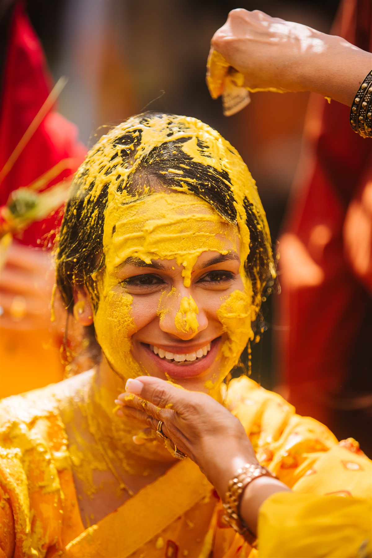 The bride, mid-haldi, laughing through turmeric