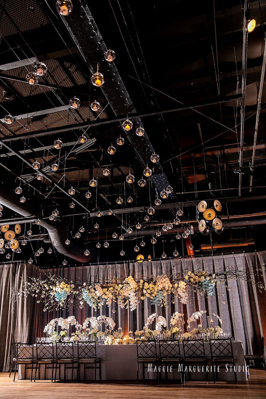 The head table beneath its floral canopy, candle orbs above
