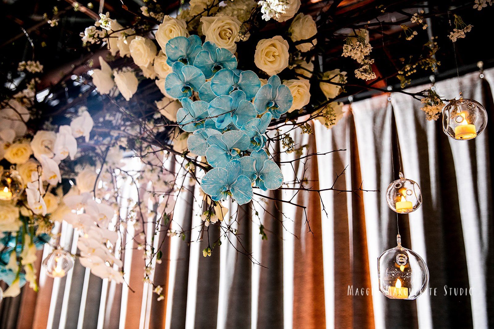 Blue orchids and cherry blossom overhead, candlelight in glass orbs